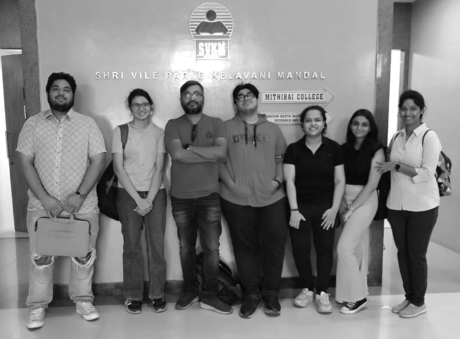 Swapnil with a group of students in front of the Mithibai College sign
